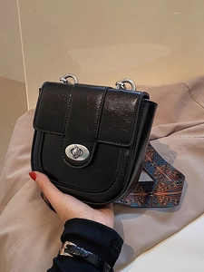 Minimalist black patent leather saddle bag with colorful bohemian wide shoulder strap