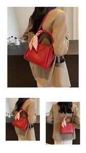 Gros plan du sac seau en cuir grainé rouge avec foulard décoratif et détail de boucle
