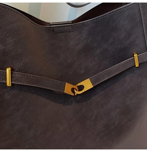 Close-up of pebble leather texture and gold buckle hardware on a vintage tote bag