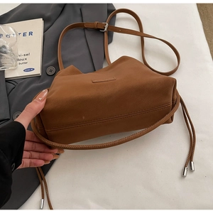 Detail of caramel brown bucket bag featuring soft leather pleats and metal cord ends