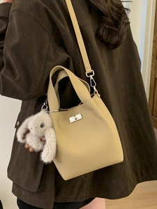 Minimalist beige leather bucket bag with silver lock and plush rabbit pendant