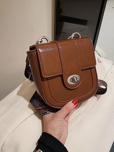 Brown vintage saddle bag with ethnic printed strap and silver twist lock in hand