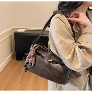 Détail du sac rétro marron foncé avec ferrures dorées et breloque ours en peluche mauve