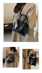 Détail du sac cabas en cuir noir avec poignée en foulard de soie et logo embossé