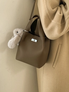 Brown lychee leather bucket handbag with silver lock and plush bunny charm accessory