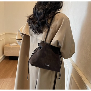 Detail of dark brown frosted leather bucket bag with drawstring and branded metal plaque