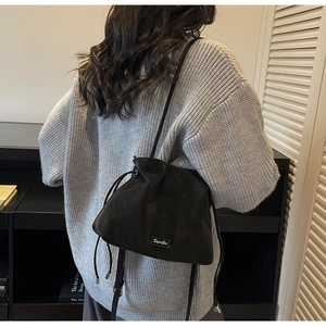 Model back view of a chic matte black drawstring bucket bag paired with a gray knit sweater
