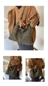 Detail of olive green leather tote bag with white stitching and cute teddy bear charm