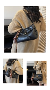 Détail du sac sous l'aisselle en cuir noir avec boucle dorée et breloque ours en peluche
