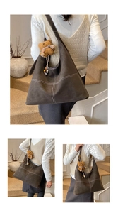 Detail of dark grey hobo bag with contrast stitching and brown teddy bear charm