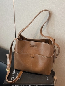 Vintage brown leather bucket bag with wide shoulder strap and textured soft surface
