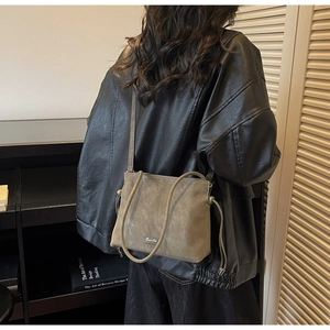 Detail of a matte khaki bucket bag with drawstring shown on a model in a minimal setting