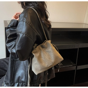 Detail of khaki bucket bag showing matte leather texture and silver logo plaque