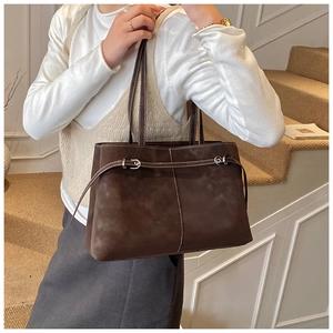 Detail of dark coffee suede tote bag featuring contrast stitching and leather strap buckles