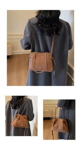 Detail of caramel brown matte leather bucket bag with drawstring and metal logo plate