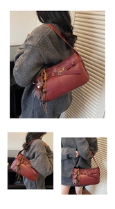 Détails d'un sac à bandoulière vintage rouge foncé avec anneaux en métal et breloque