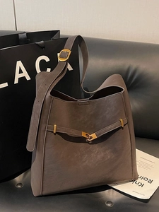 Vintage large dark brown tote bag in lychee leather with golden buckle on a sofa