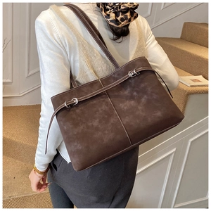Detailed view of brown suede tote bag featuring white contrast stitching and metal buckle