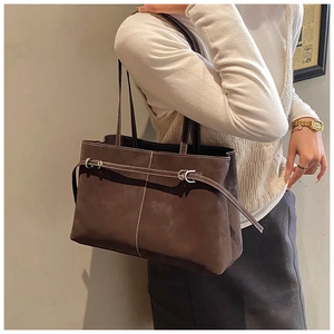 Detailed close-up of dark brown suede tote bag with white stitching and metal buckle