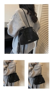 Detail of black soft leather drawstring bucket bag with adjustable shoulder strap and logo
