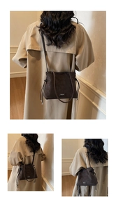 Detailed view of dark brown leather drawstring bag with textured finish and slim strap