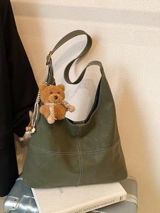 Vintage dark green hobo bag with white cross-stitching and cute brown bear pendant charm