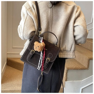 Detail view of retro brown faux leather satchel with bear charm and striped ribbon