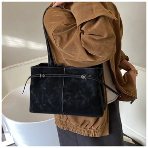 Detail of matte black leather tote bag featuring white contrast stitching and minimalist design