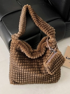 Brown plush tote bag with textured grid pattern and matching pouch on leather chair