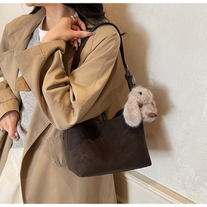 Borsa tote in pelle opaca marrone scuro con ciondolo a coniglio su una modella