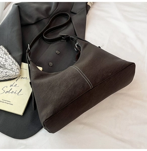 Detailed view of dark brown hobo bag with contrast stitching and matte texture