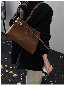 Brown suede tote bag with white stitching detail worn over the shoulder by a model