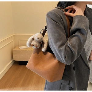 Dettaglio borsa tote in pelle scamosciata marrone con ciondolo a coniglio in peluche