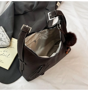 Detail of dark brown hobo bag showing pebbled leather texture and silver buckle strap