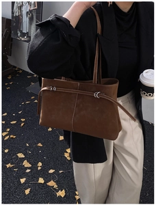 Detail of brown suede tote bag with silver buckle and white stitching in street style view