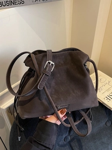 Deep brown matte suede bucket bag with adjustable strap and silver metal buckle