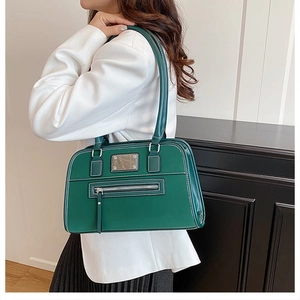 Détail du sac à bandoulière en similicuir vert foncé avec des surpiqûres blanches contrastées