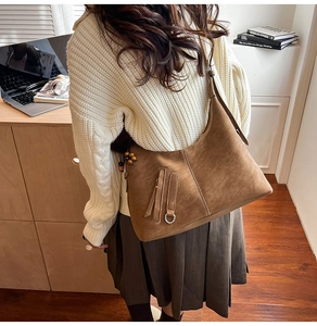 Detail of caramel suede shoulder bag with tassels and wooden beads in a study setting