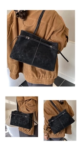 Detail of black suede tote bag featuring white contrast stitching and silver metal buckle