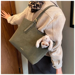 Detail of olive green suede tote bag with adjustable strap and plush rabbit charm