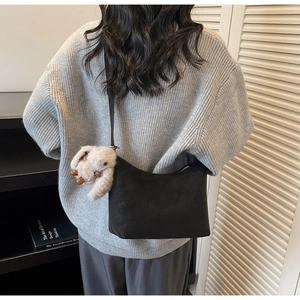 Borsa hobo nera minimalista con ciondolo a coniglio in peluche indossata da una modella