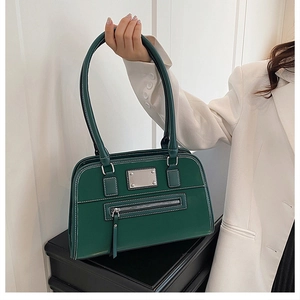 Détail du sac à bandoulière en cuir vert foncé avec surpiqûres blanches et métal argenté