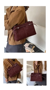 Close-up of burgundy suede tote bag featuring white contrast stitching and silver buckle