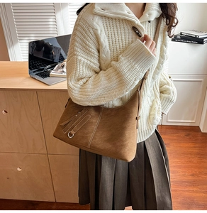 Detail of a brown suede hobo bag with tassel accent against a cozy autumn outfit