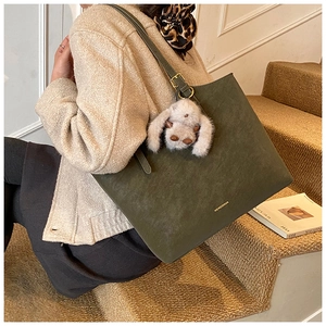 Detail of olive green suede tote bag with plush rabbit charm and adjustable strap
