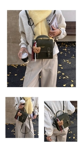 Detail of dark green leather handbag featuring fashion text and a plush bear charm accessory