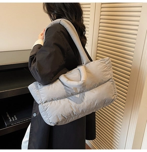 Gros plan sur le sac fourre-tout matelassé gris clair montrant la texture et la bandoulière