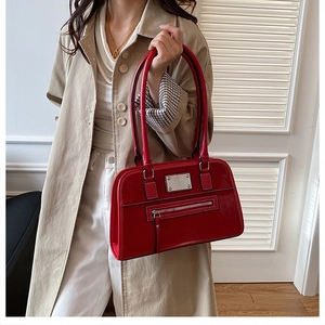 Gros plan sur un sac à bandoulière en cuir verni rouge avec détails métalliques brillants