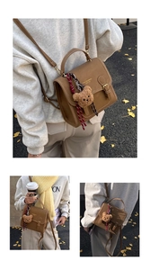 Brown vintage faux leather backpack with plush bear charm and buckle detail in outdoor setting