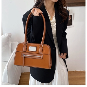 Détail du sac bandoulière en similicuir marron caramel avec finitions argentées et zip